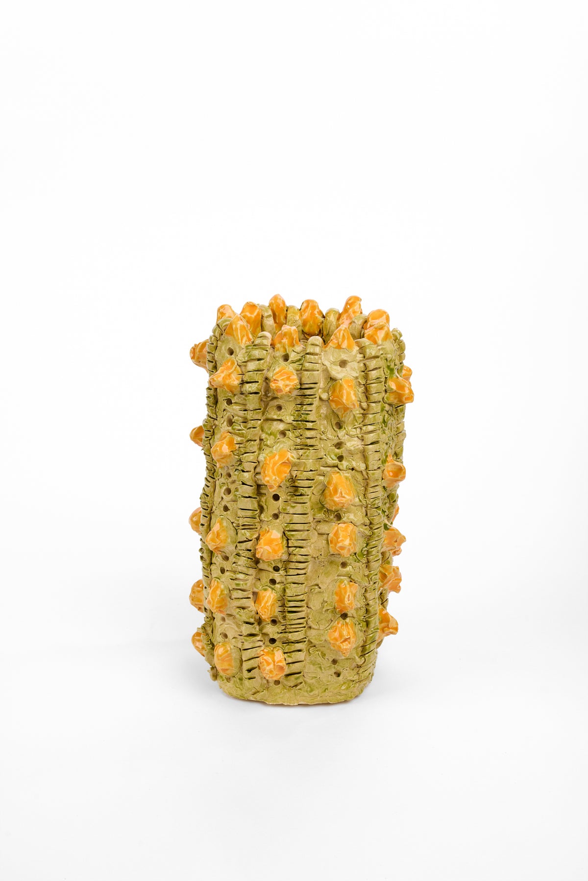 Tall cylindrical olive-green ceramic vase with an uneven rim. Vertical ridges, small holes, and raised orange bud-like forms cover the textured surface.