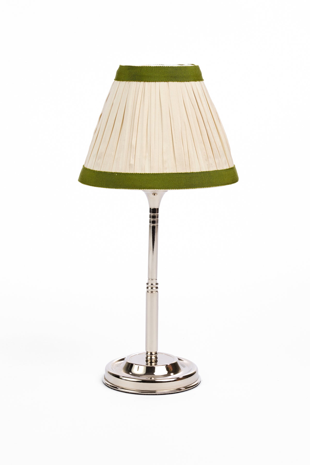 A vintage-style table lamp with a pleated cream shade trimmed in olive green, mounted on a polished silver metal stem and base, set against a plain white background.