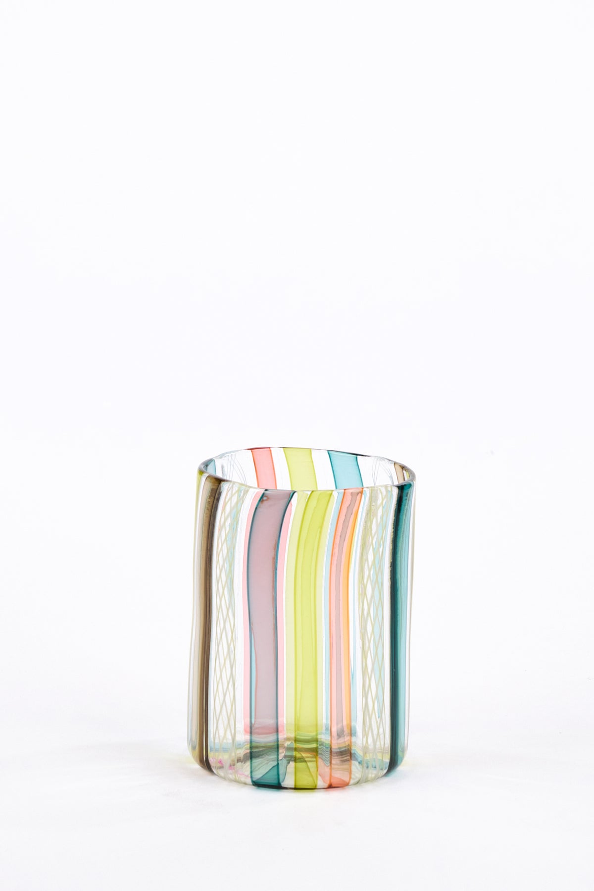 A small cylindrical glass tumbler with vertical multicolor stripes in pastel pink, , green, blue, and orange on a white background.