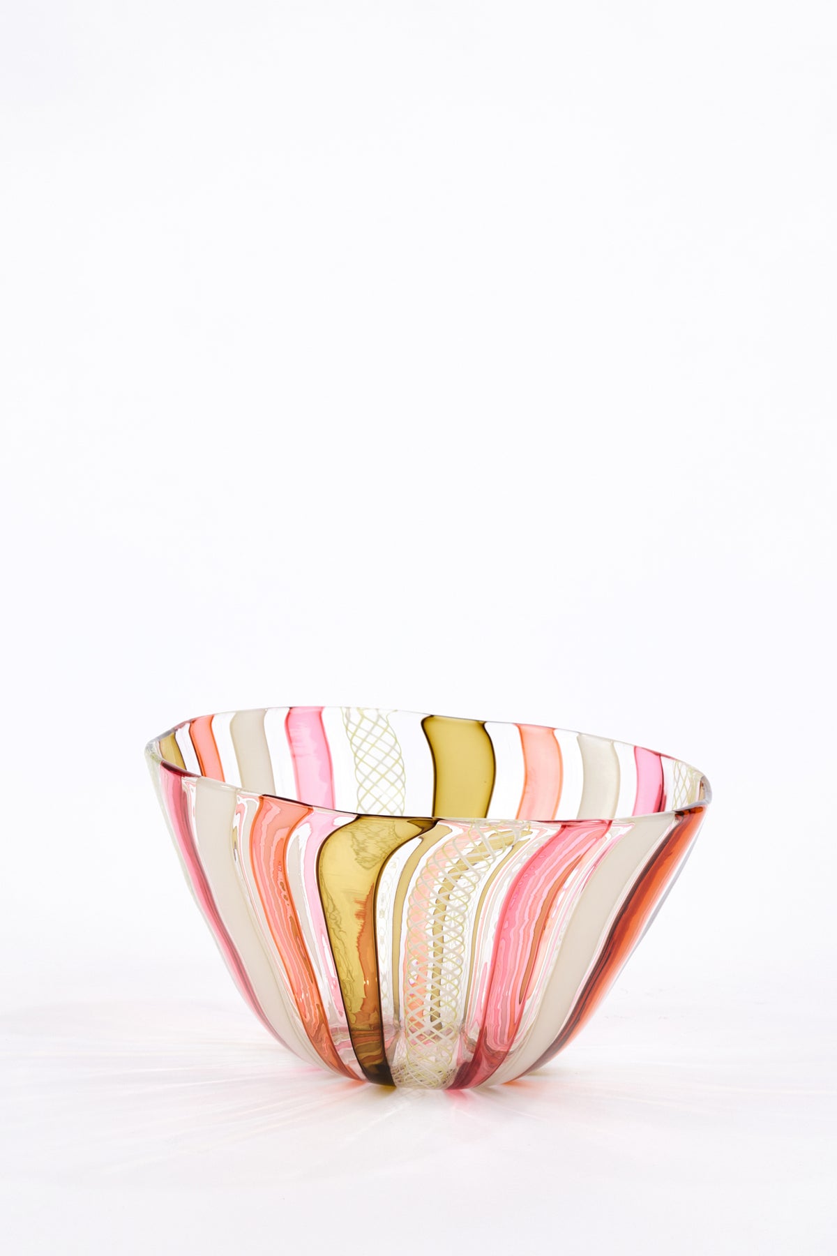 A hand-blown glass bowl with vertical wavy stripes in pink, orange, gold, and cream, set against a plain white background.