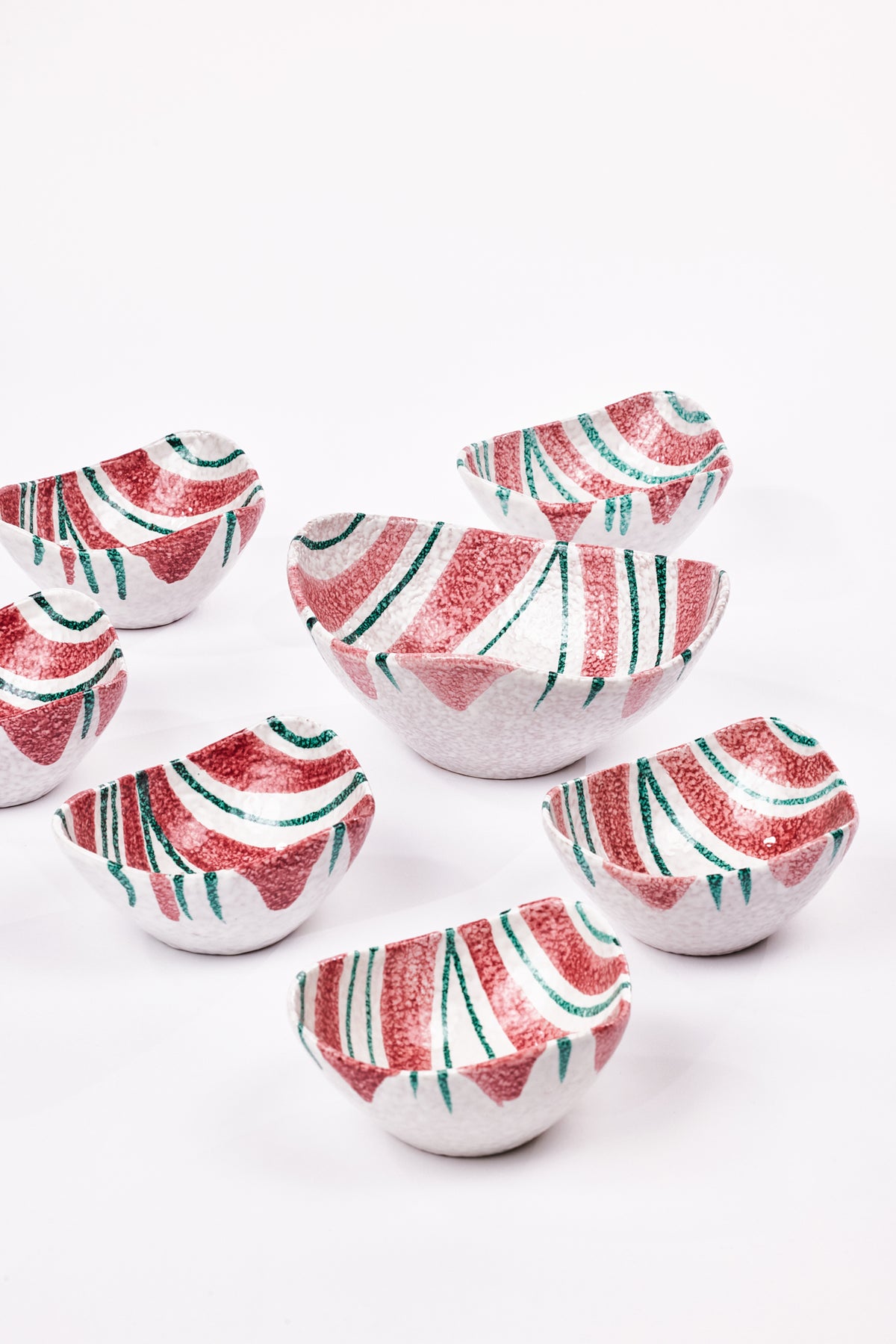Set of  7 irregularly shaped bowls with red and green stripes on the interior,  all varying slightly in size and style. 