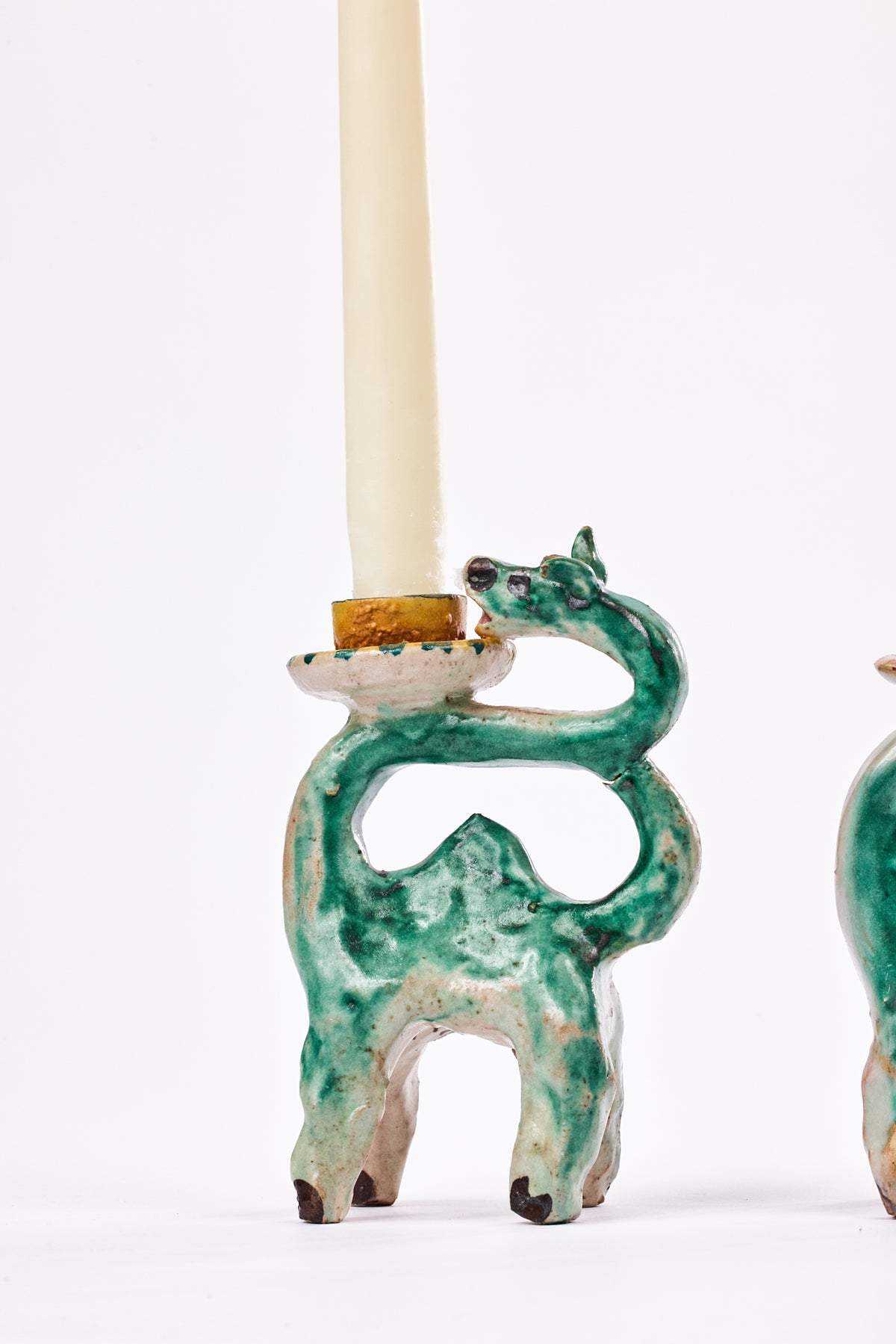 A ceramic donkey-shaped candle holder in a green glaze with a cream-colored candle inserted, photographed against a plain white background.