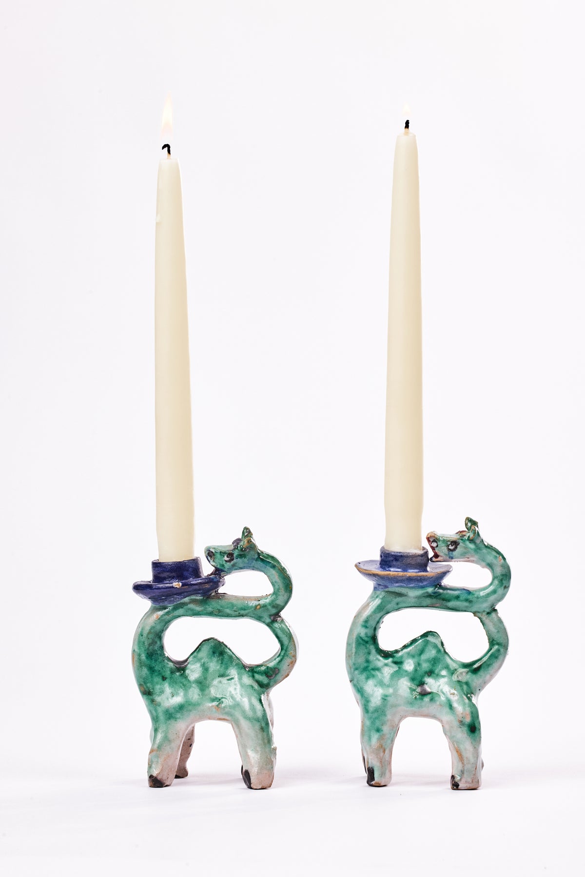 abstract handmade ceramic green-glazed donkey candleholders with off-white unit taper candles.
