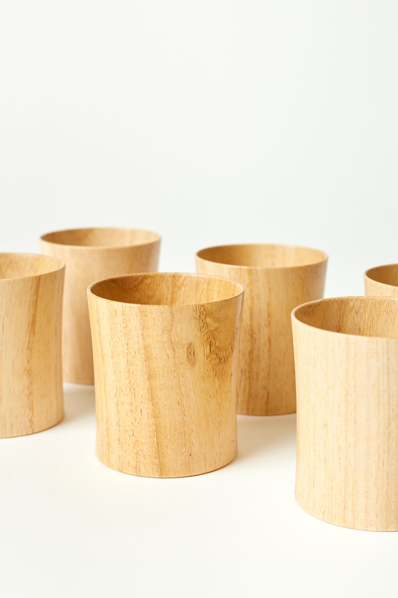 Wooden tumblers made from Paulownia wood, photographed against a white background. 