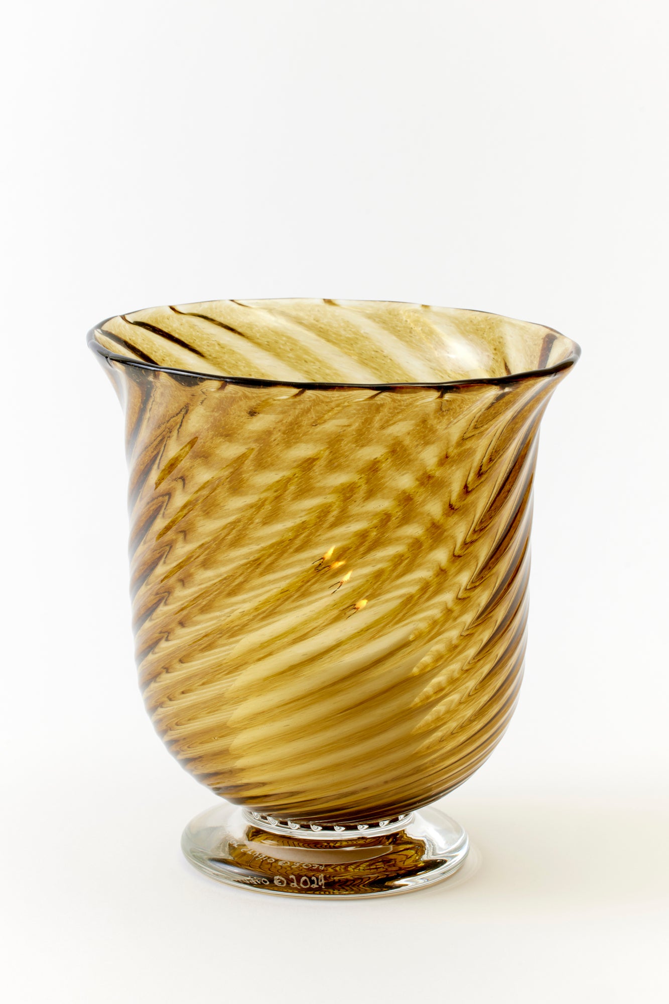 Elegant amber-hued glass vase with a swirling, hand-blown design, featuring a wide flared rim and a clear pedestal base. The intricate, textured glasswork adds a touch of vintage sophistication, making it a statement piece perfect for candles, floral arrangements and as a standalone décor item.