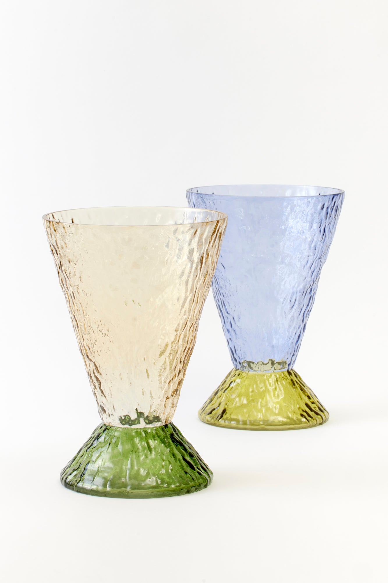 Elegant textured glass goblets in soft beige and icy blue, each featuring a sculpted green and yellow base. Perfect for a sophisticated table setting or stylish bar cart decor.