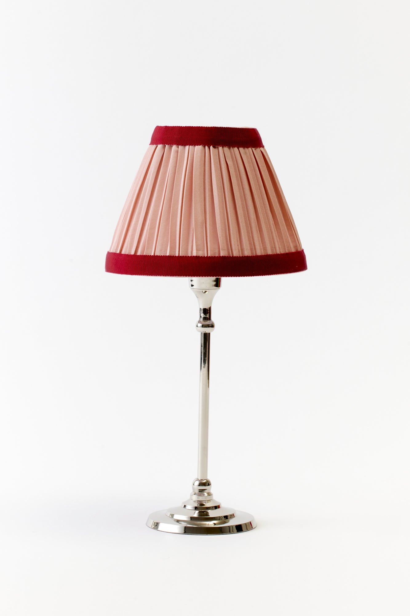 Pleated pink table lamp with red trim.