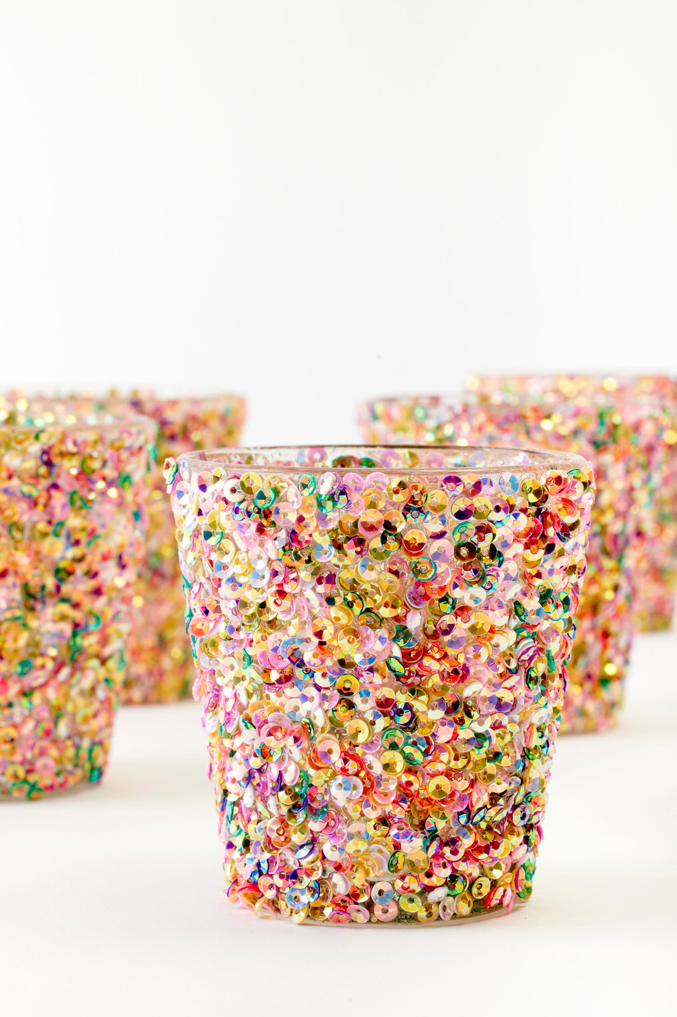 Close-up of a glittering glass votive adorned with a kaleidoscope of colorful sequins. The intricate detailing and reflective surface create a captivating, festive look, ideal for adding a bold, celebratory sparkle to any table setting or party décor.