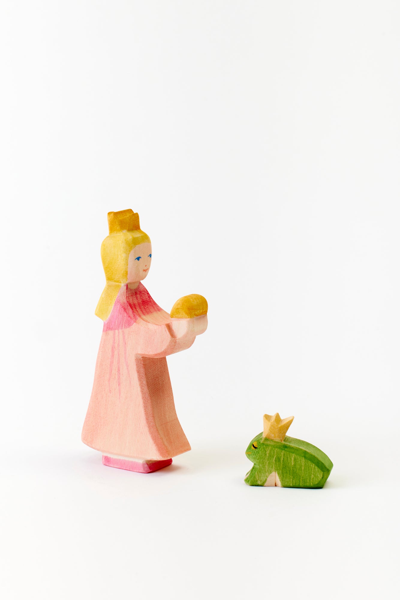 Fairytale meets handcrafted elegance: a blonde princess, crowned and serene, extends a golden ball towards a royal green frog. Simplicity and charm in one modern fantasy.