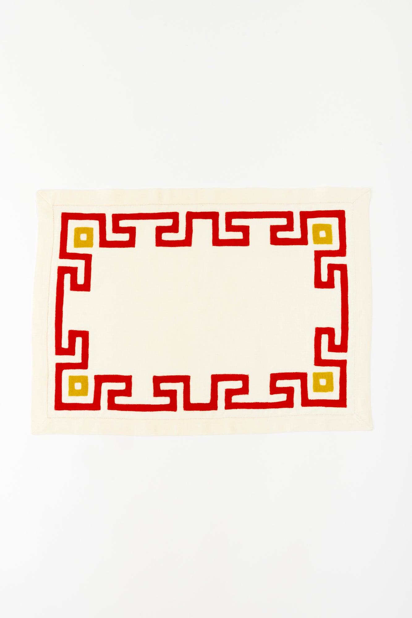 Cream linen placemat and napkin set with bold red and yellow geometric border embroidery, ideal for stylish and modern table décor.