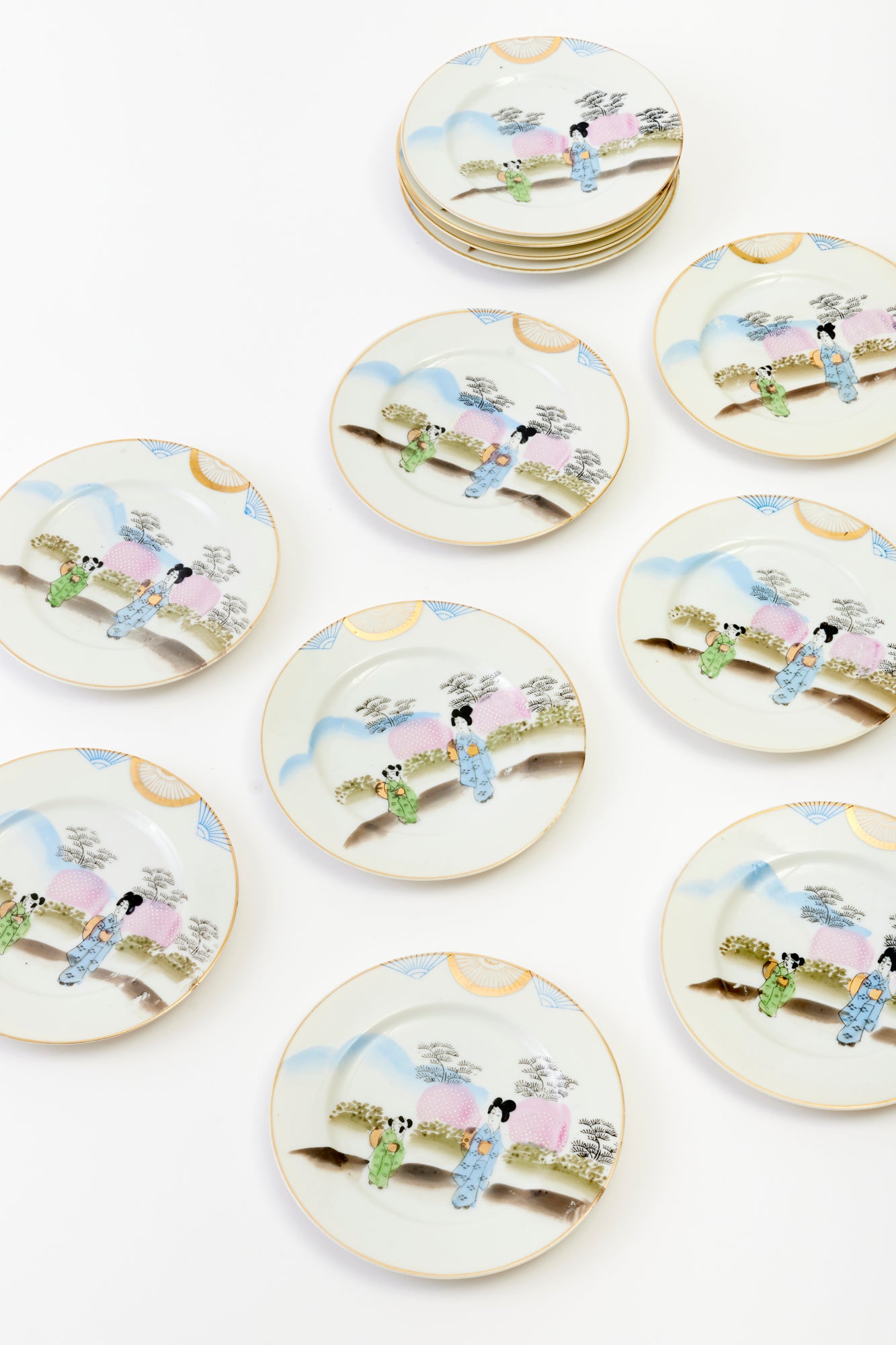 Set of decorative plates featuring hand-painted figures in traditional Japanese attire, with gold and pastel accents.