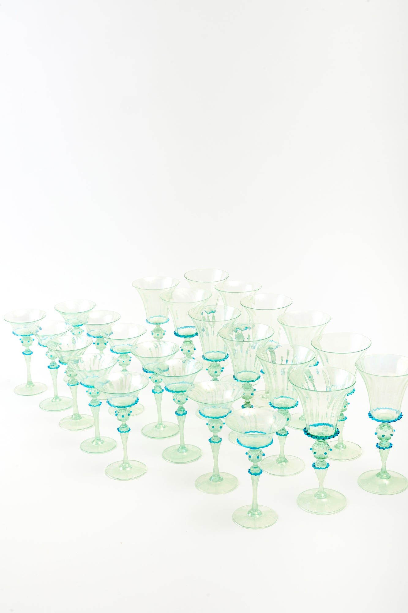 Set of elegant vintage Venetian green glass goblets and coupes with blue decorative accents on the stems.