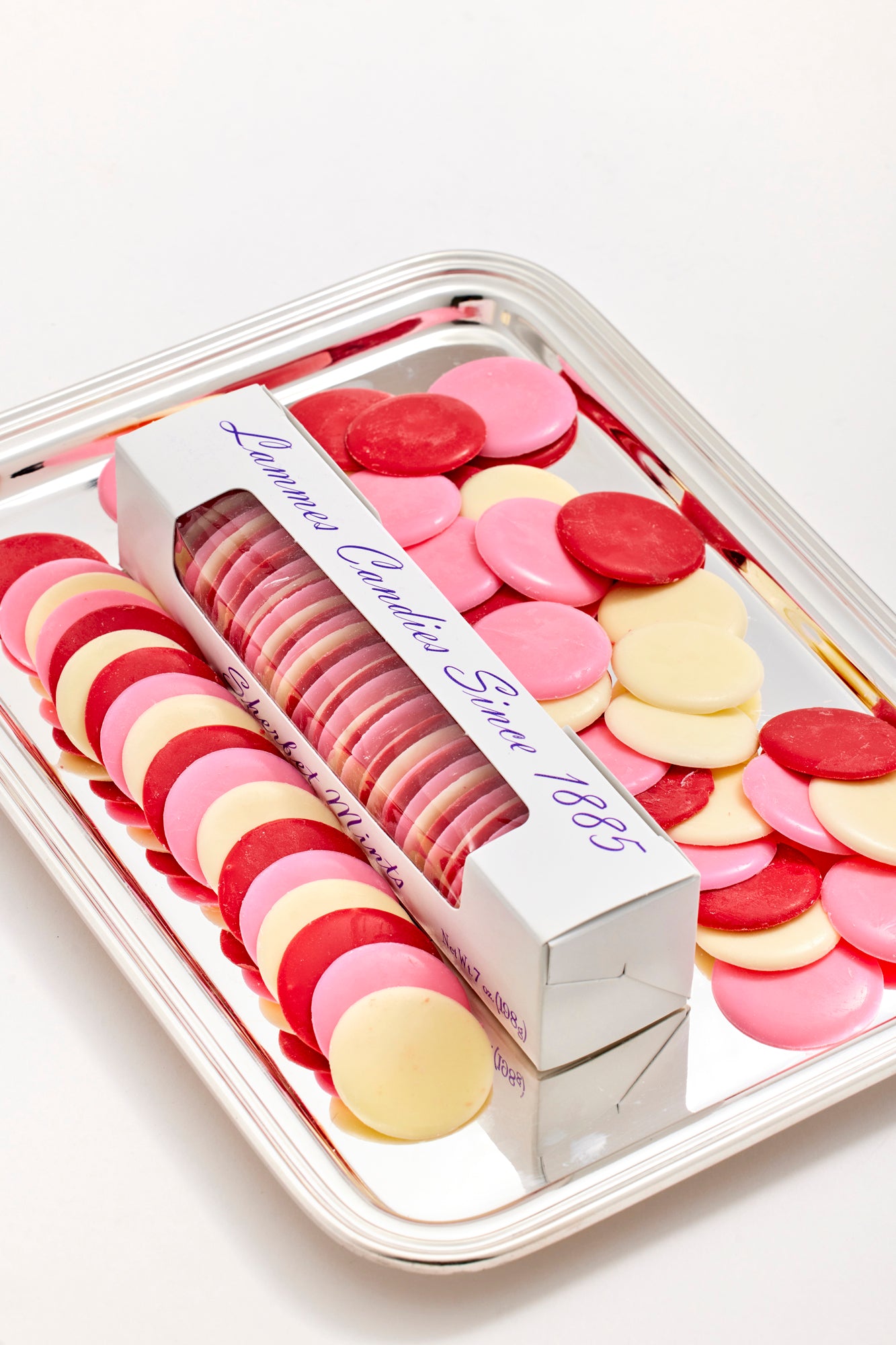 Assorted pink, red, and white candy mints from Lammes Candies on a silver tray.