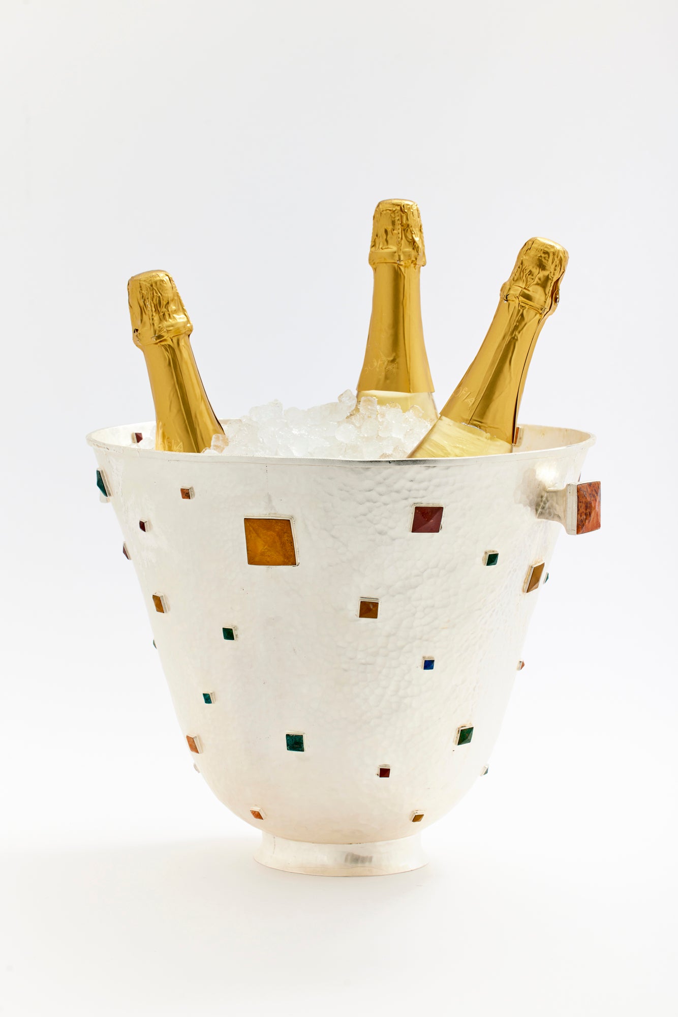 Luxurious hammered silver champagne cooler with inlaid semi-precious stones, filled with ice and holding three bottles of champagne. The geometric gemstone design adds a touch of sophistication and modern elegance, making it the perfect centerpiece for a chic celebration or upscale event.