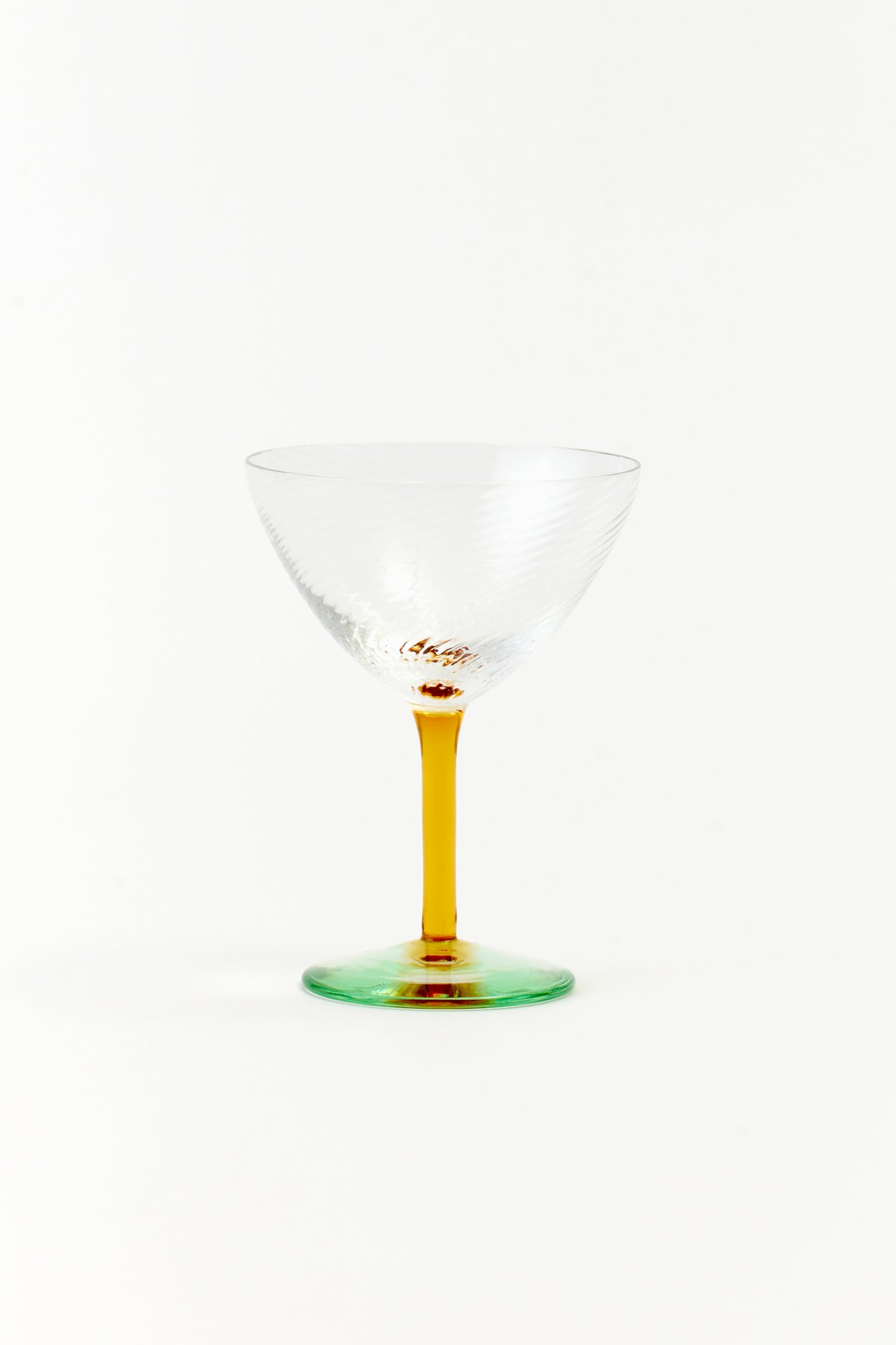 Handblown in Murano, these glasses feature a honey-colored stem and twisted clear coupe, perfect for serving effervescent Champagne or elevating cocktails.