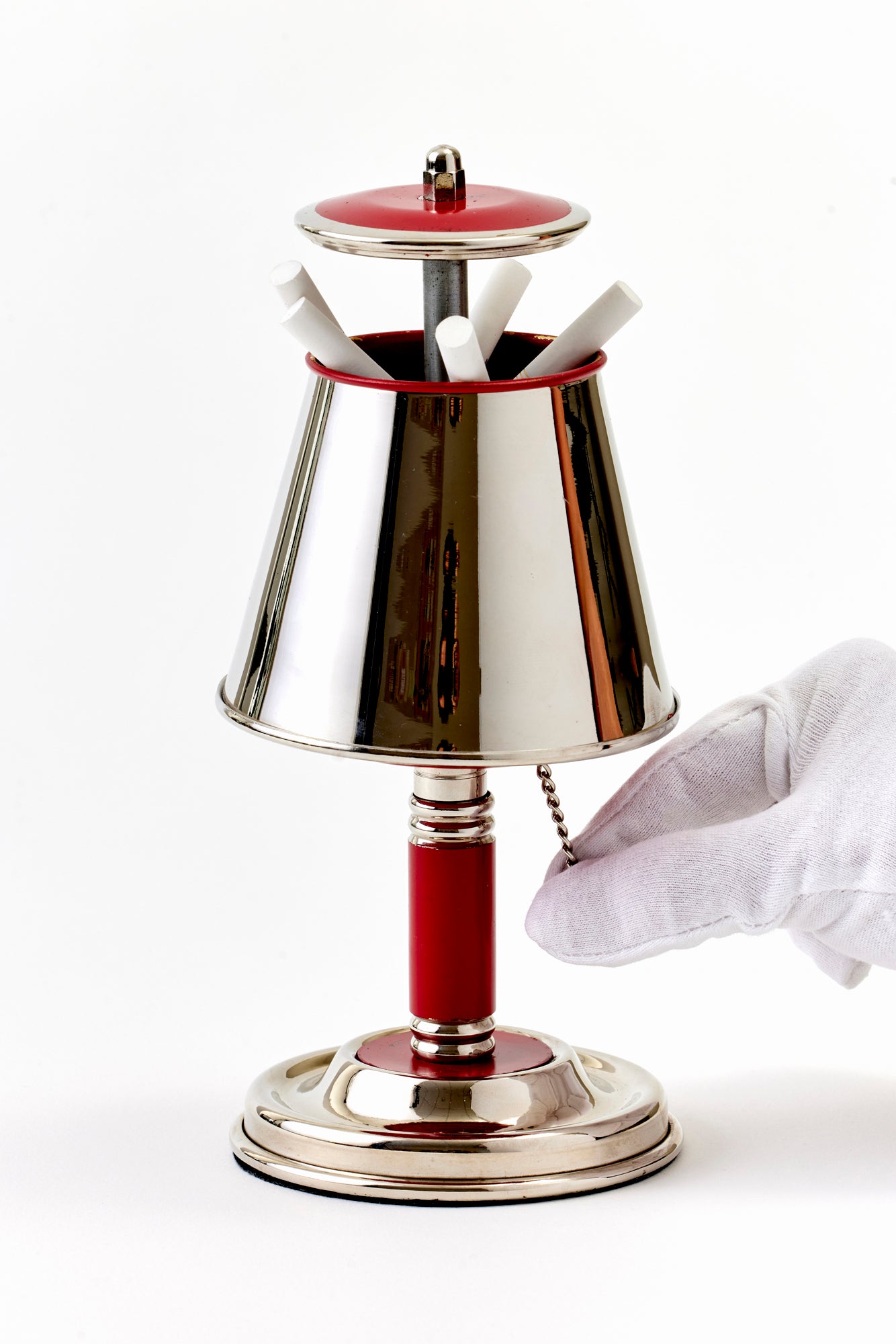 Decorative cigarette dispenser with red and silver design on a white background