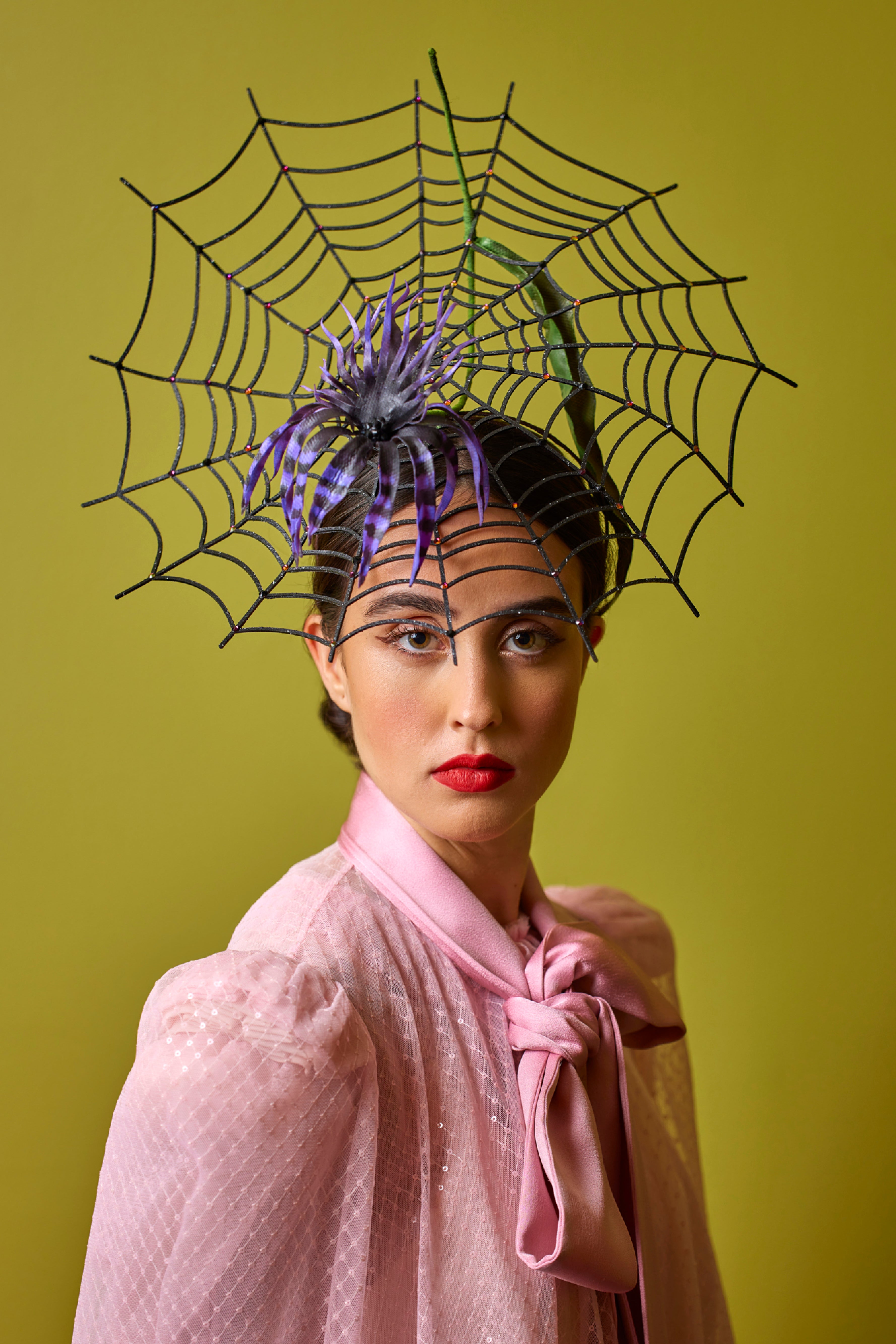 A headpiece shaped like a spider web, with a black and purple striped spider at the center.