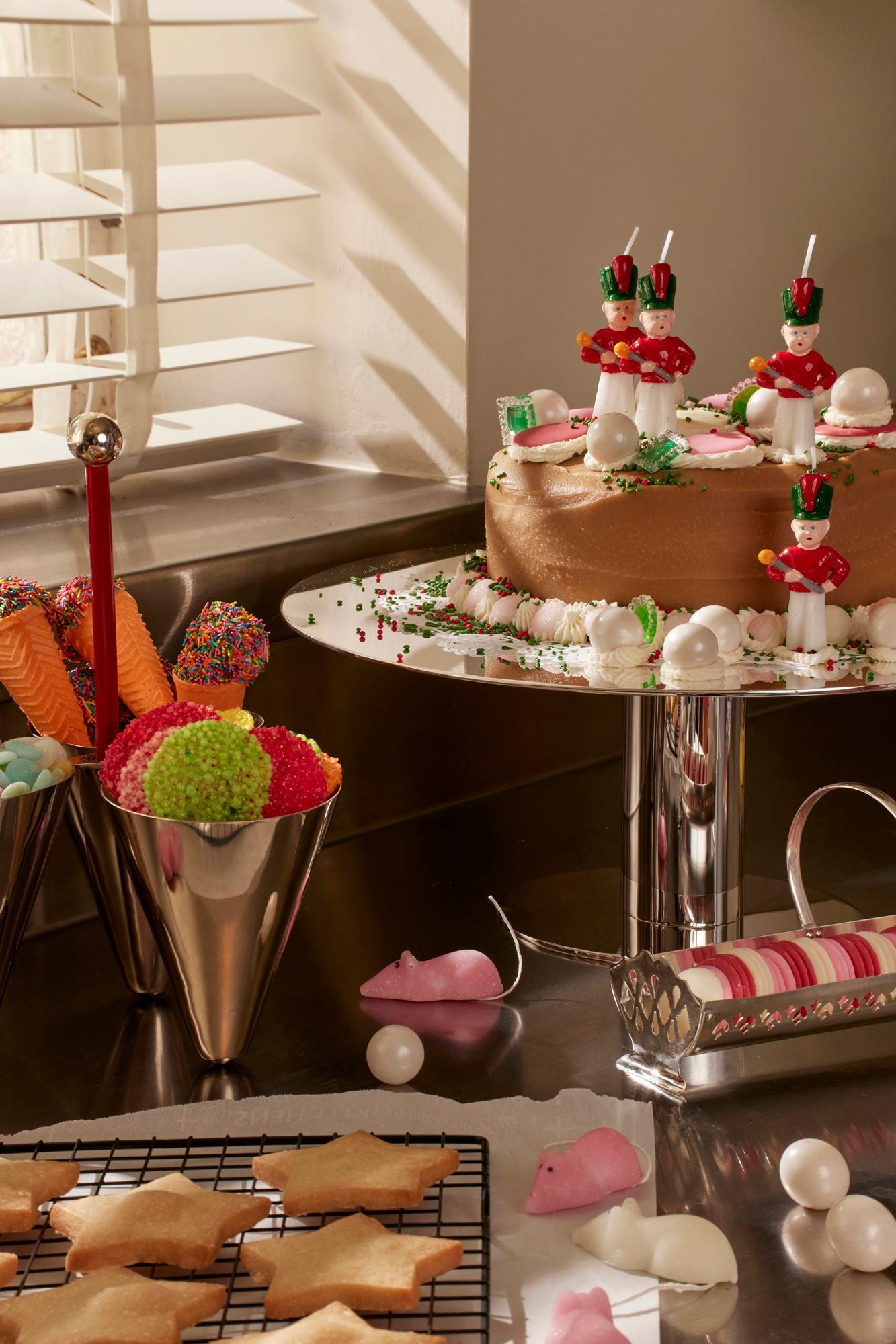 Decorative table setting with gingerbread cookies, candy, and a cake in a kitchen.