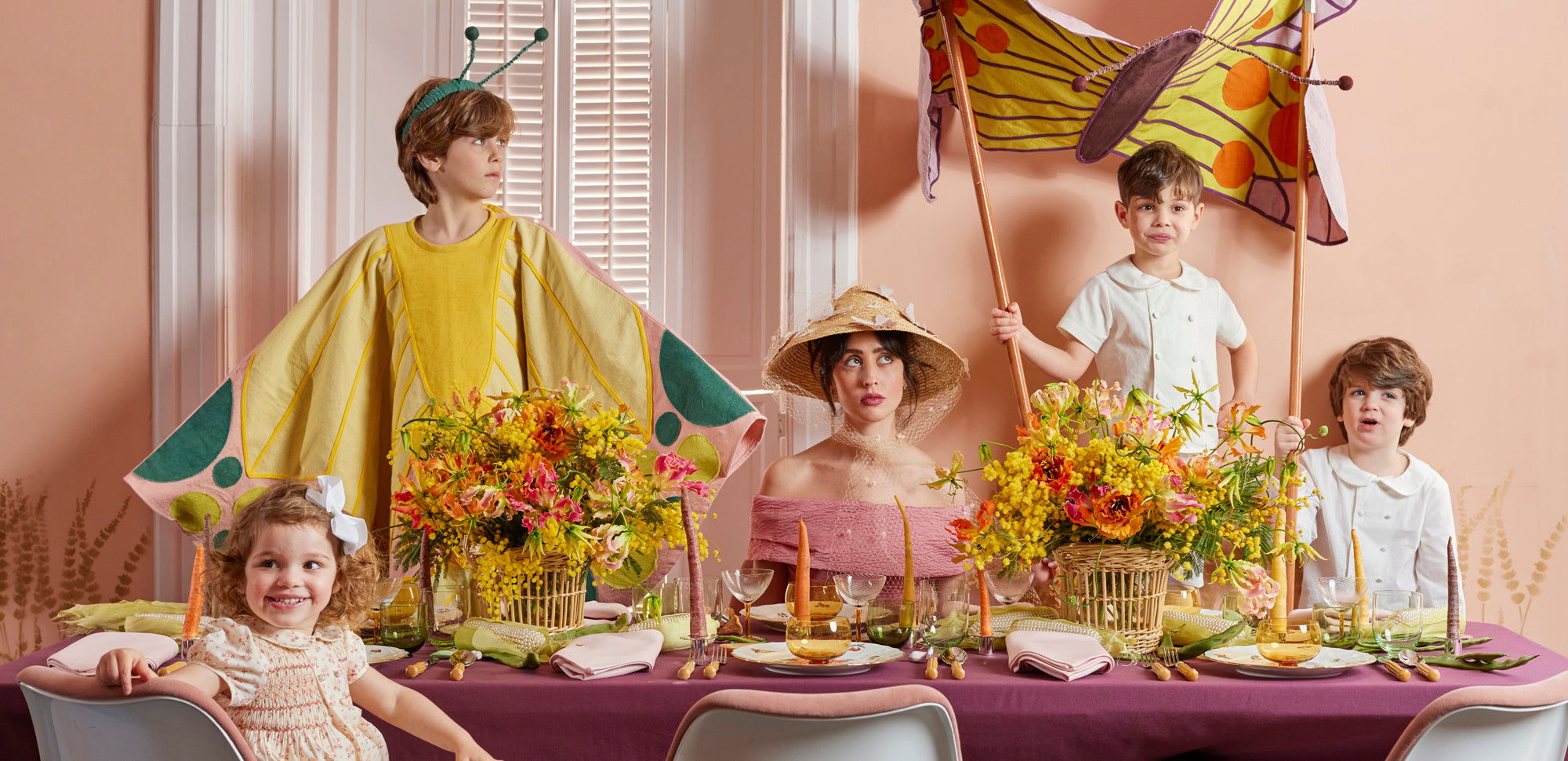 Woman and children sitting at colorful easter table with butterfly parade kite