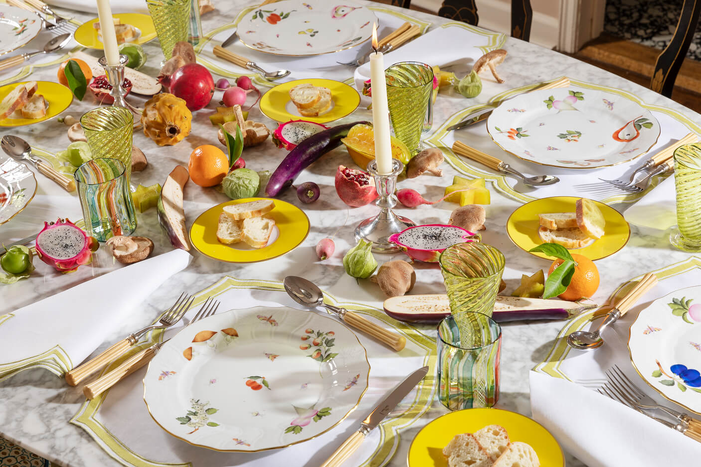 Table with porcelain, candles, colorful glassware and fruits