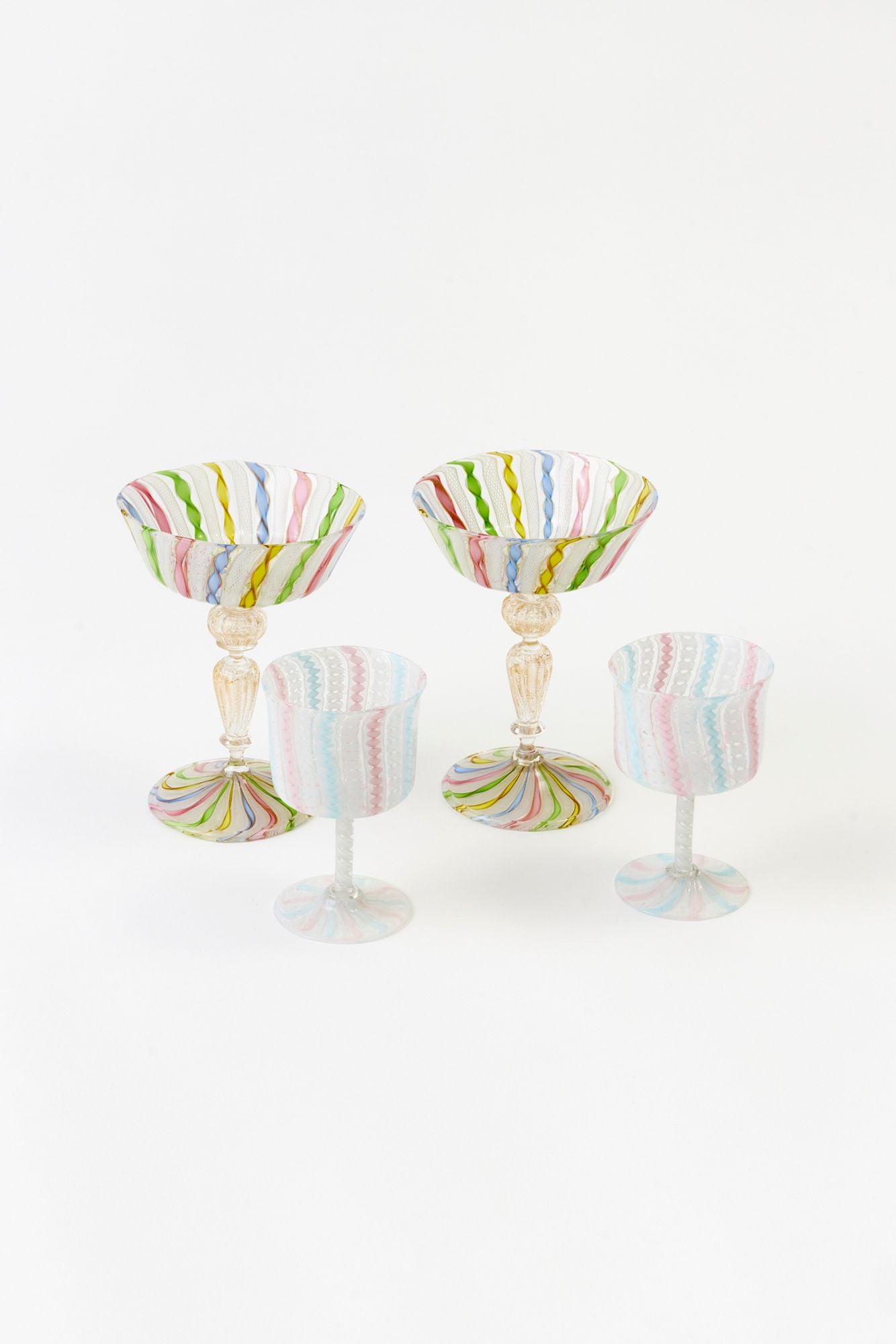 Set of four multicolored striped cocktail glasses on a white background