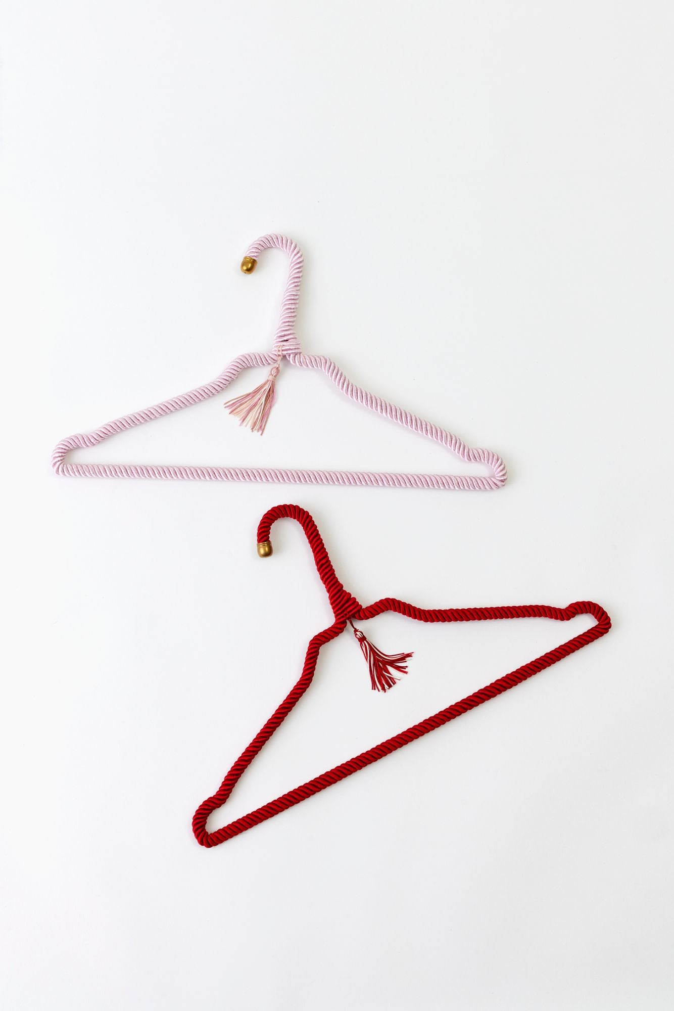 Red and pink wrapped hangers with tassels on a white background