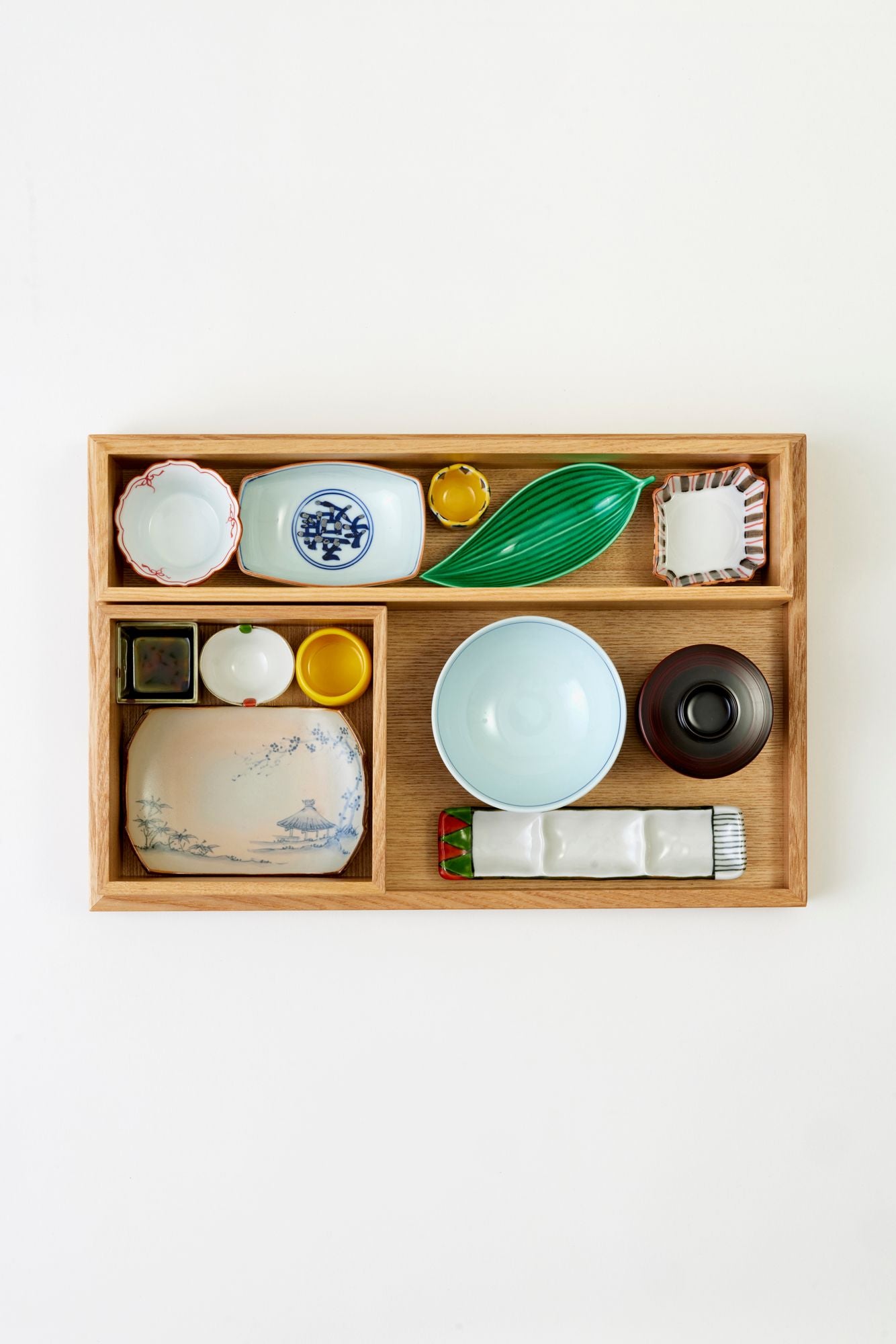 Wood bento box with Japanese dishes on a white tablecloth