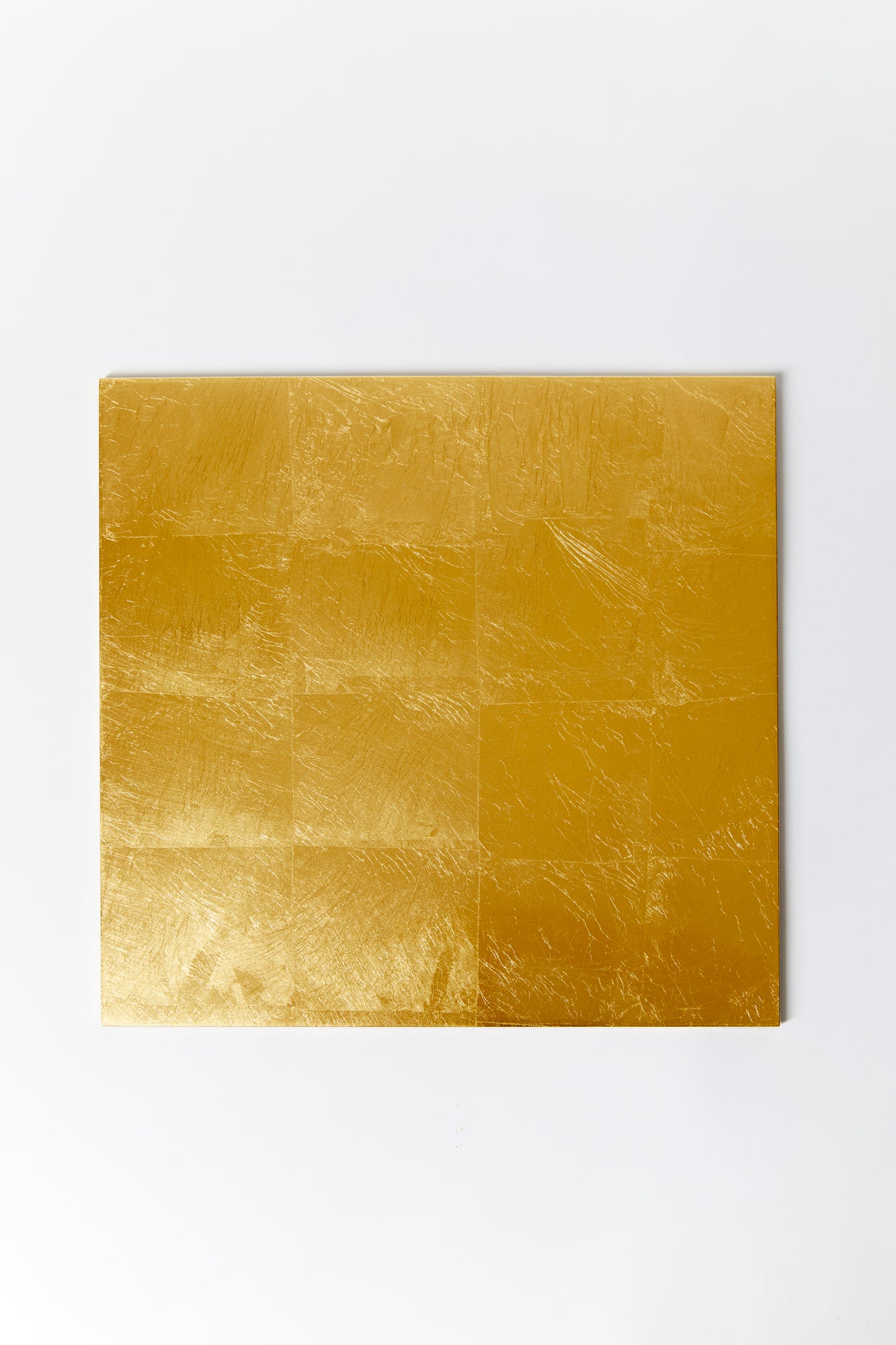 Square gold placement photographed against a white background. Placemat is gold leaf and lacquer and offers a glistening effect. 