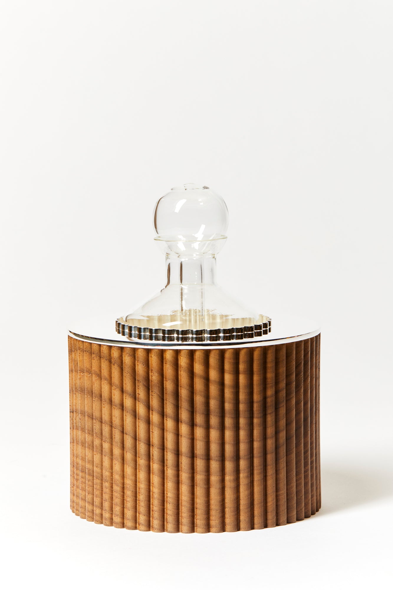 Oil dispenser made of silver-plated metal, American walnut, and glass, photographed against a white background. 