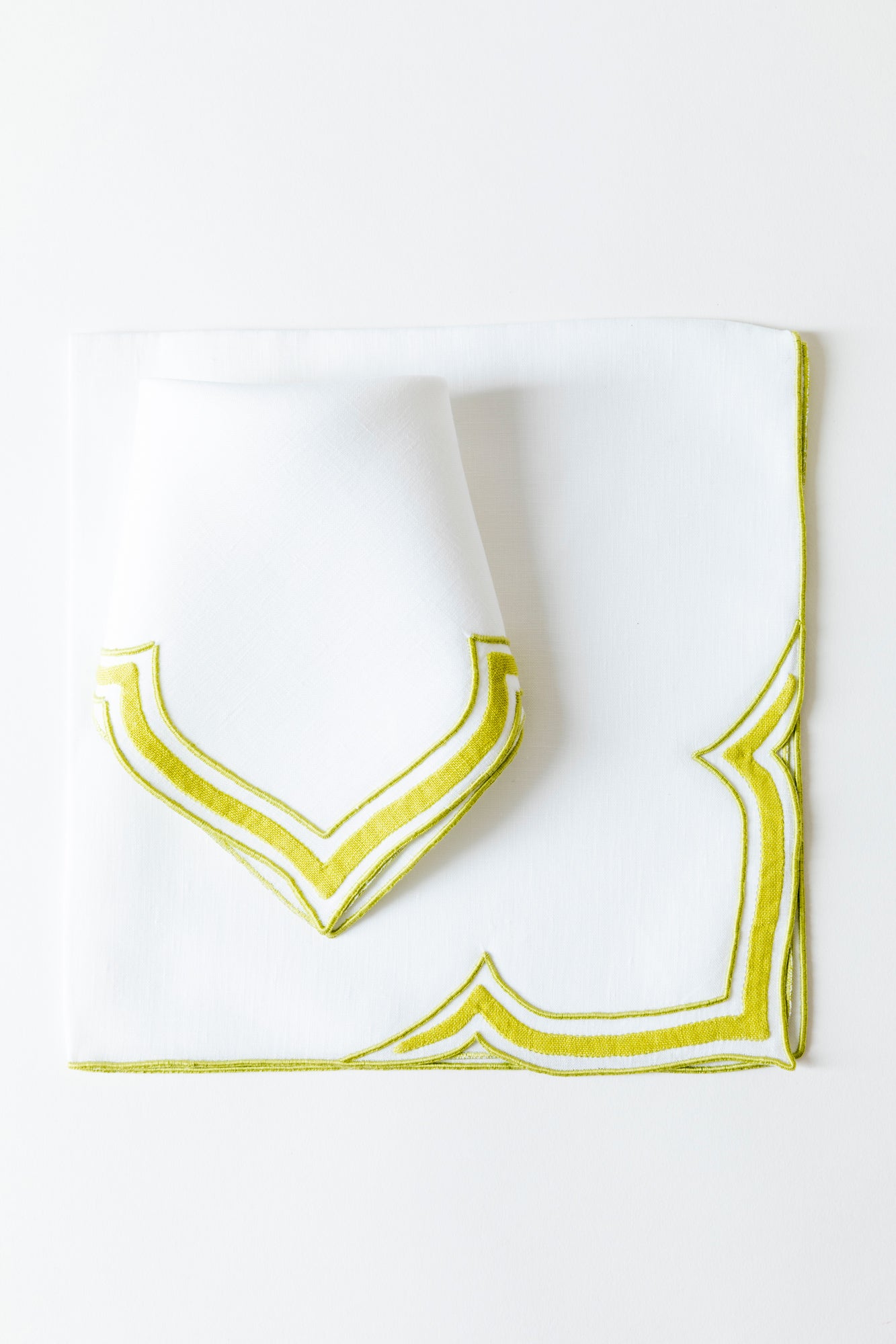 Linen dinner napkin in an unusual scalloped design with chartreuse embroidery and French stitch appliqué made in Madeira, Portugal.