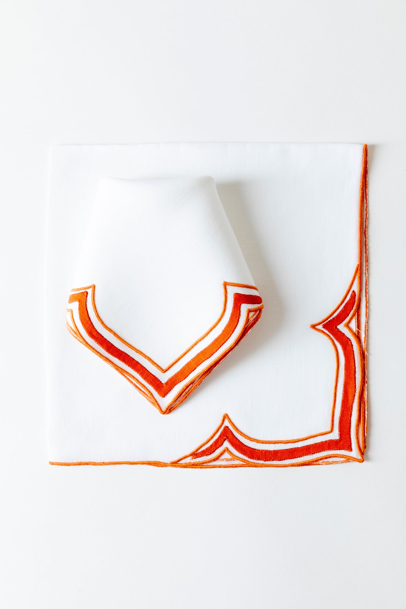 Tangerine linen placemat in an unusual scalloped design with embroidery and French stitch appliqué made in Madeira, Portugal.