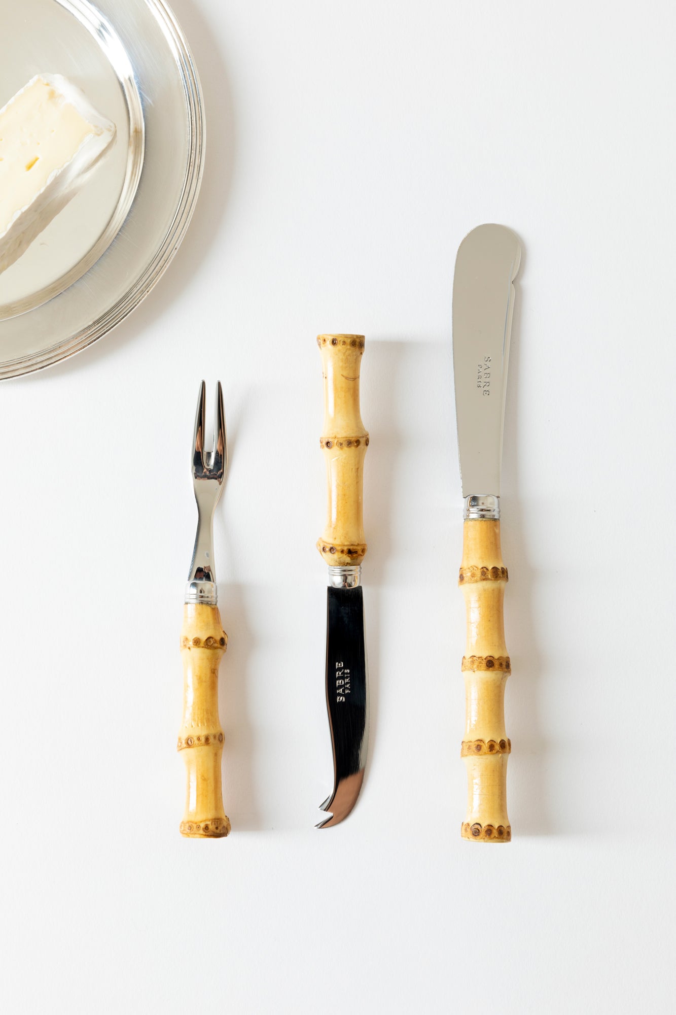 Bamboo charcuterie tools including a cheese knife, cocktail pick and butter spreader.