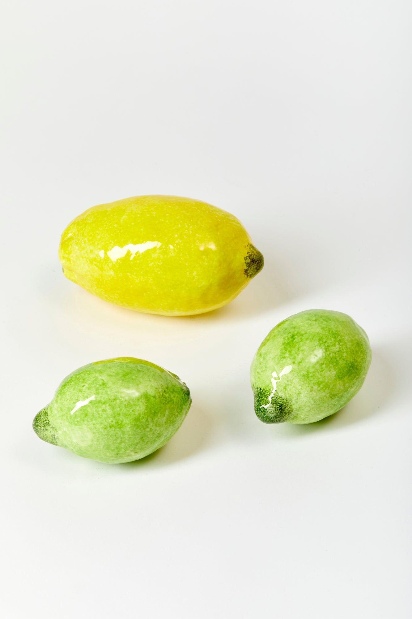 2 ceramic limes and 1 ceramic lemon against a white background. 