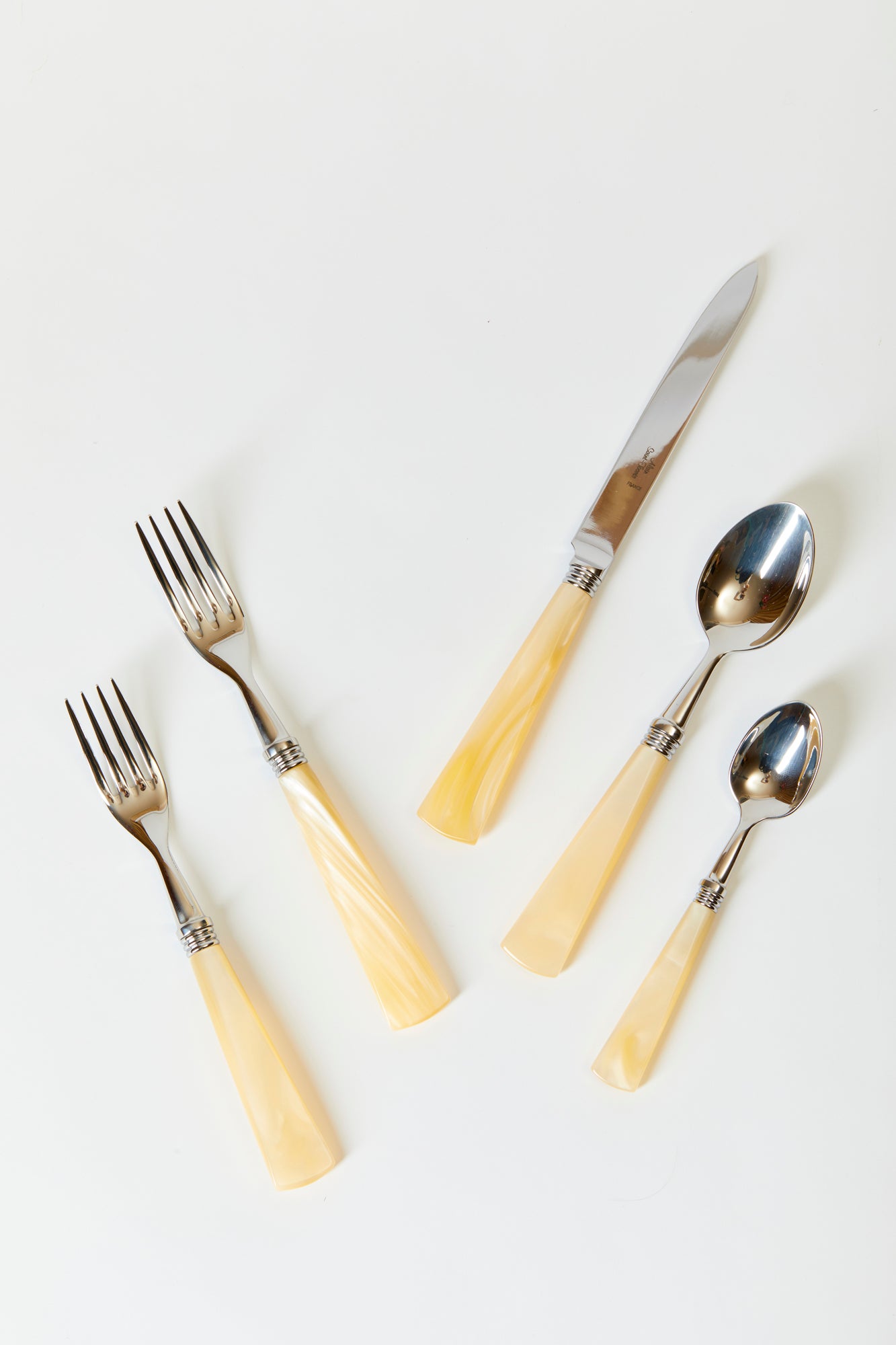 The set of five Mother of Pearl flatware includes a dinner knife, dinner fork, salad fork, dessert spoon, and tea spoon. Made in France in stainless steel with silver plate and simulated nacre.