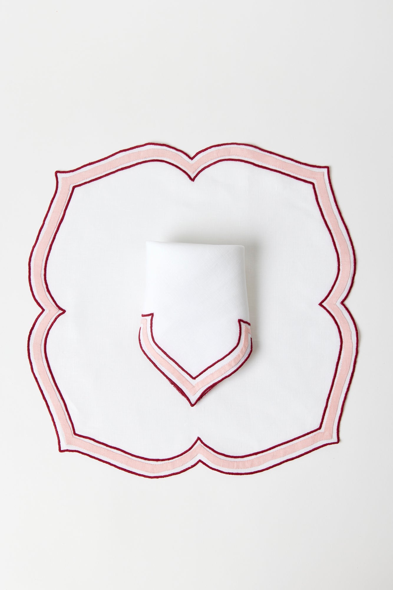 Crimson and crepe colored linen dinner napkin in an unusual scalloped design with embroidery and French stitch appliqué made in Madeira, Portugal.
