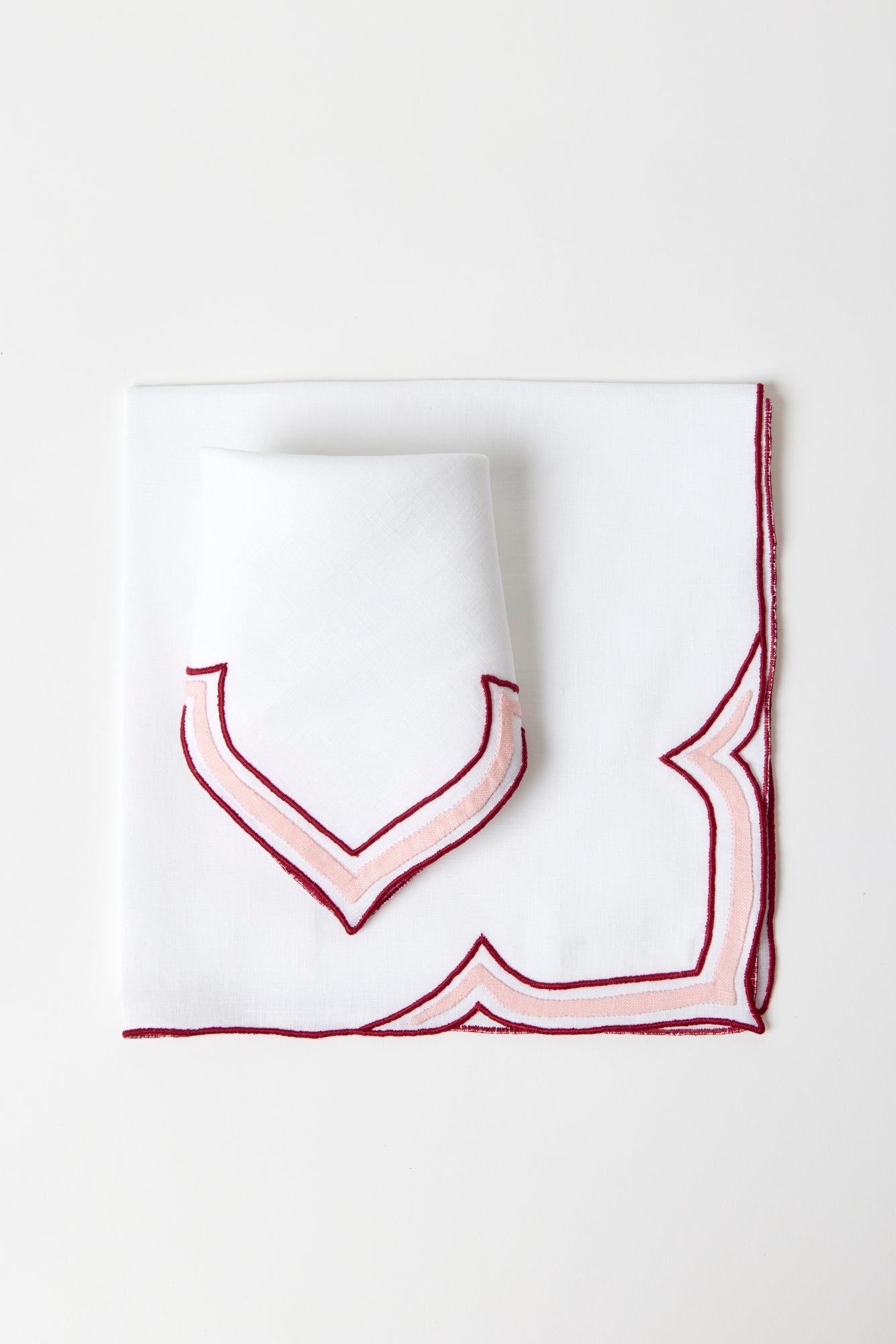 Crimson and crepe colored linen dinner napkin in an unusual scalloped design with embroidery and French stitch appliqué made in Madeira, Portugal.